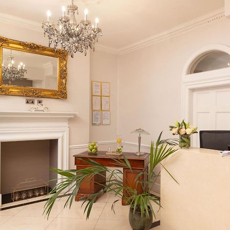 Hotel Montcalm Brewery Townhouse Londyn Zewnętrze zdjęcie The photo shows a stylish reception area. There is a decorative chandelier hanging from the ceiling, providing elegant lighting. A large, ornate mirror is mounted on the wall beside the fireplace, which features a simple, classic design. In front of 