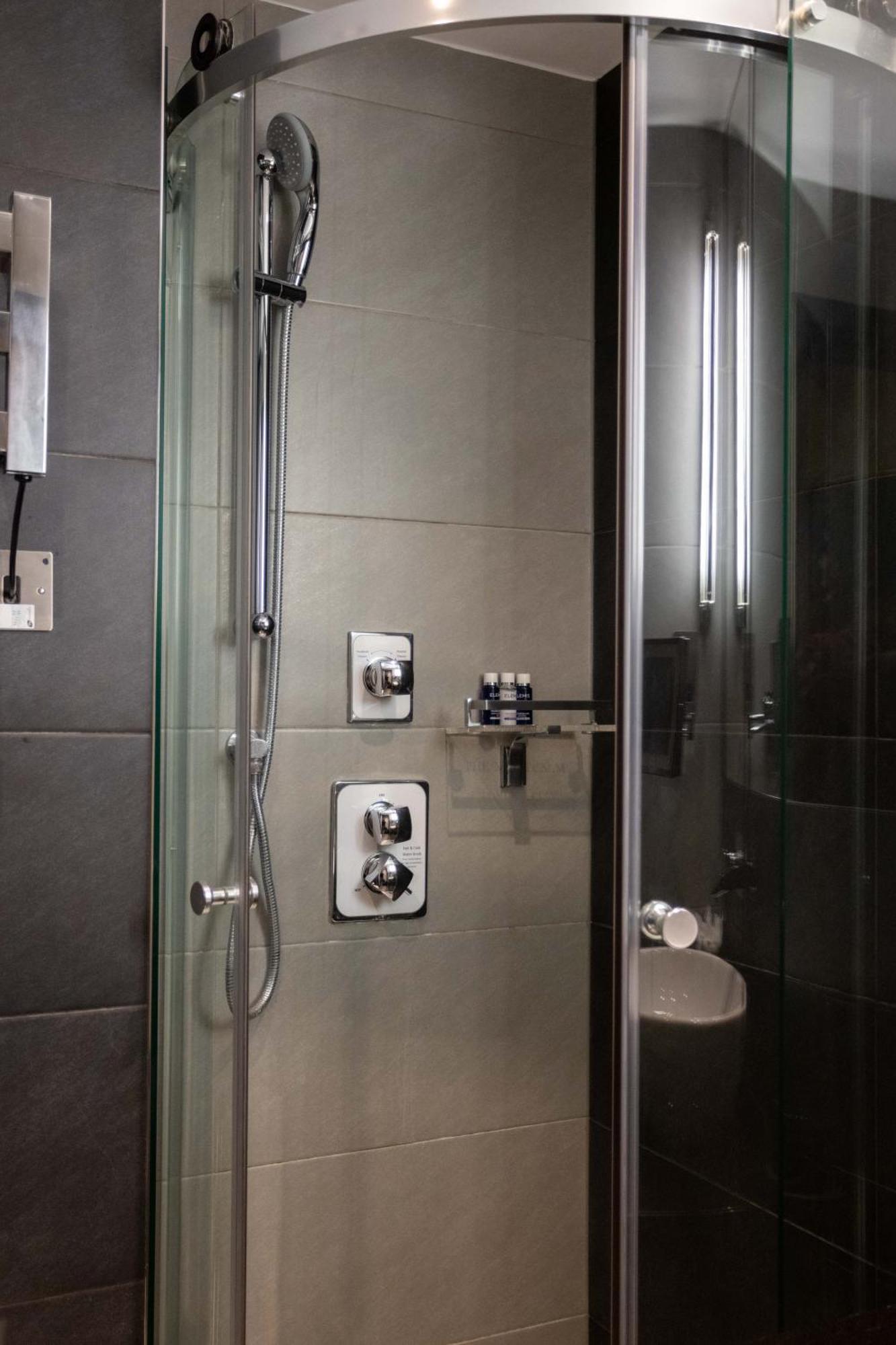 Hotel Montcalm Brewery Townhouse Londyn Zewnętrze zdjęcie The photo shows a modern shower area. It features glass panels and tiled walls in a neutral color palette, creating a sleek and contemporary look. There are two main control panels for adjusting the water temperature and pressure, with various knobs 