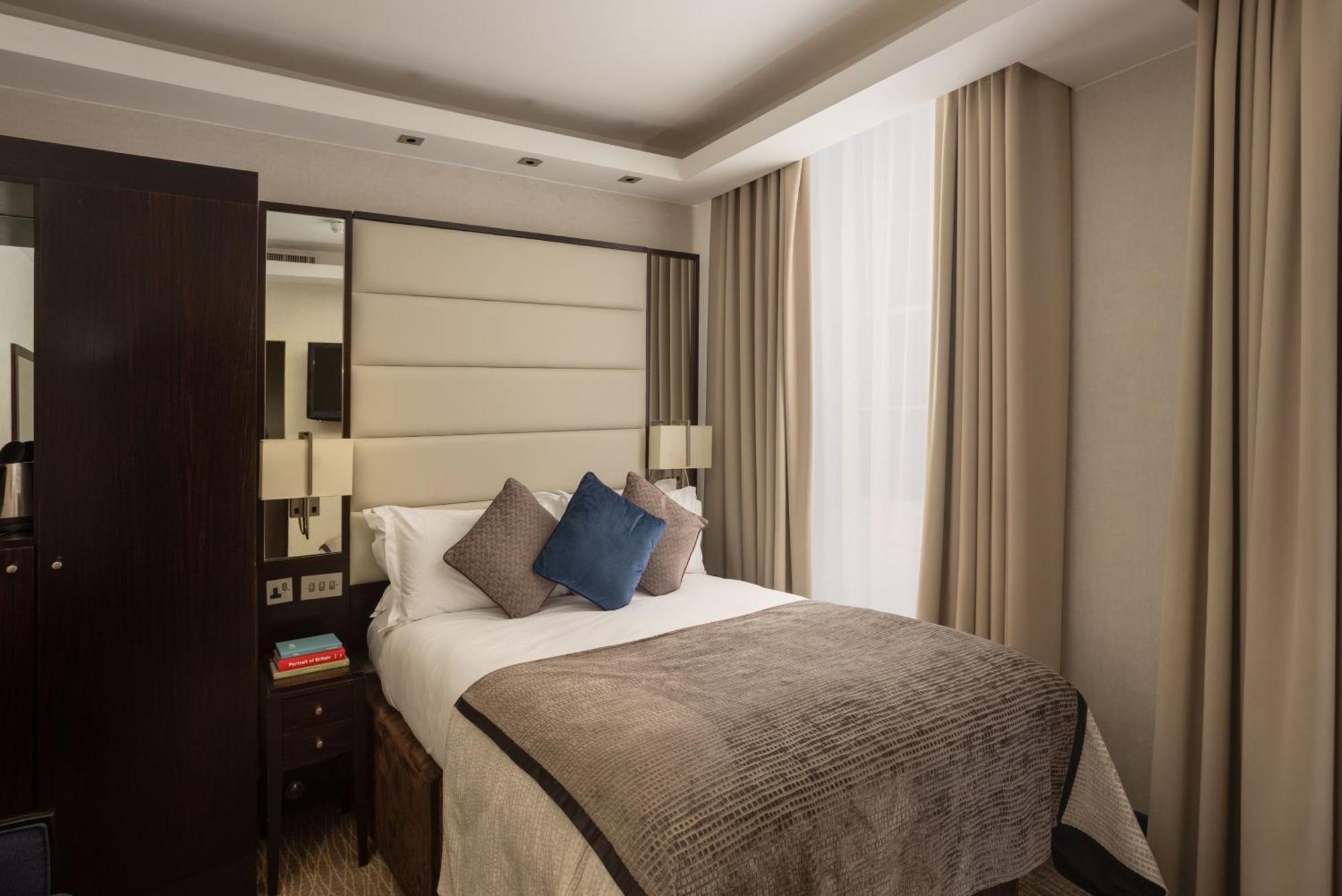 Hotel Montcalm Brewery Townhouse Londyn Zewnętrze zdjęcie The photo shows a modern hotel room with a cozy design. It features a double bed with a light-colored headboard and a soft, stylish blanket. There are decorative pillows on the bed, including a blue one. On either side of the bed, there are small nig