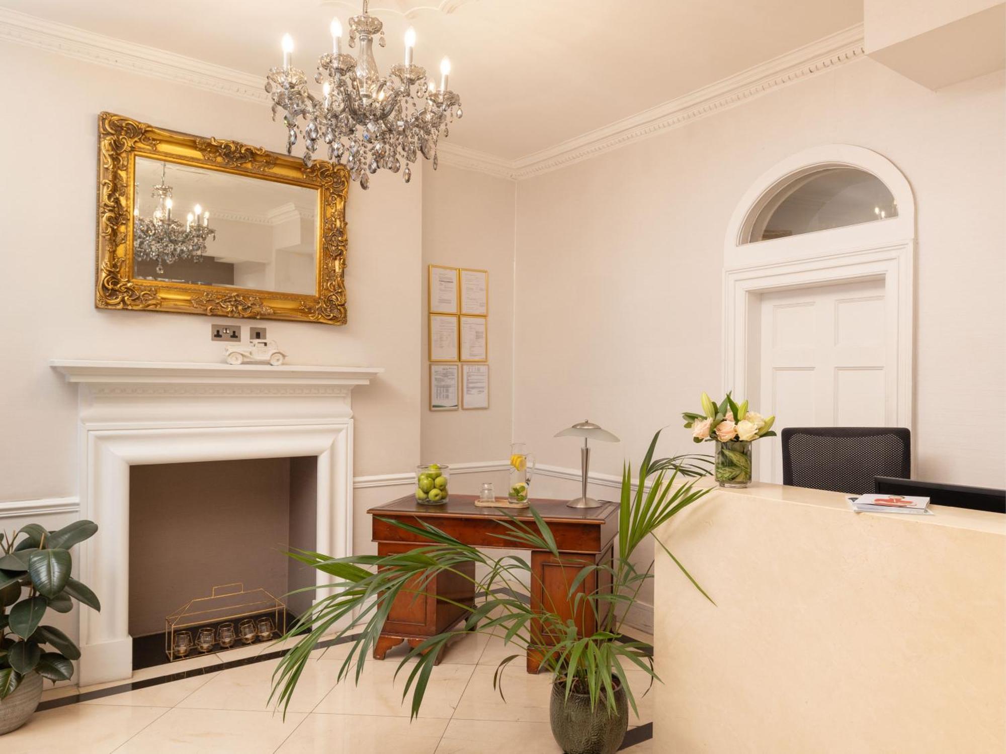 Hotel Montcalm Brewery Townhouse Londyn Zewnętrze zdjęcie The photo shows a stylish reception area. There is a decorative chandelier hanging from the ceiling, providing elegant lighting. A large, ornate mirror is mounted on the wall beside the fireplace, which features a simple, classic design. In front of 