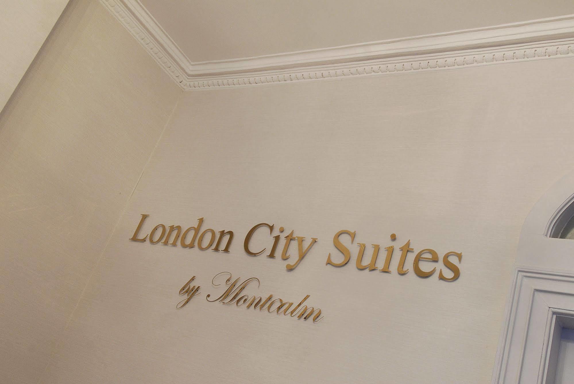 Hotel Montcalm Brewery Townhouse Londyn Zewnętrze zdjęcie The photo shows a wall display featuring the text "London City Suites" in a bold, gold-colored font. Below that, the words "by Montcalm" are written in a smaller, elegant style. The background appears to be a neutral-colored wall, possibly in a hotel