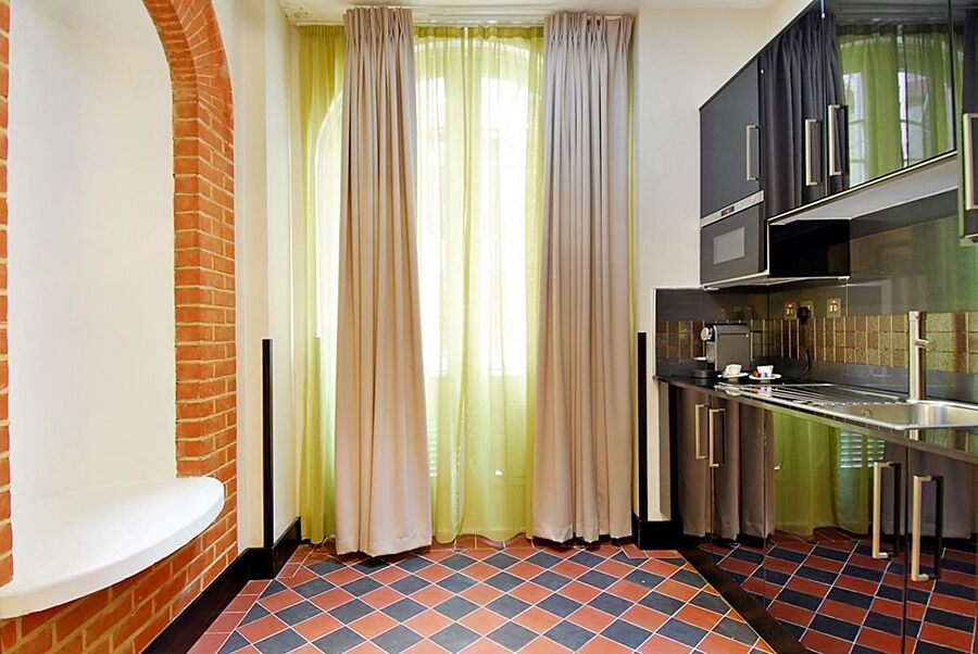Hotel Montcalm Brewery Townhouse Londyn Zewnętrze zdjęcie The photo shows a kitchen area with modern design elements. There are large, light-colored curtains hanging from the windows, allowing natural light to filter in. The walls are partially exposed brick, giving a warm texture to the room. The flooring 
