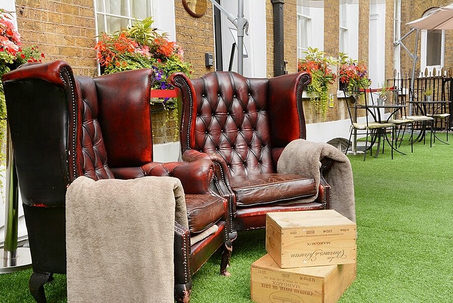 Hotel Montcalm Brewery Townhouse Londyn Zewnętrze zdjęcie The photo depicts two large, elegant armchairs with a classic design, featuring rich burgundy leather upholstery and button tufting. They are positioned in a cozy outdoor setting, with lush green artificial grass beneath them. Next to the chairs, the
